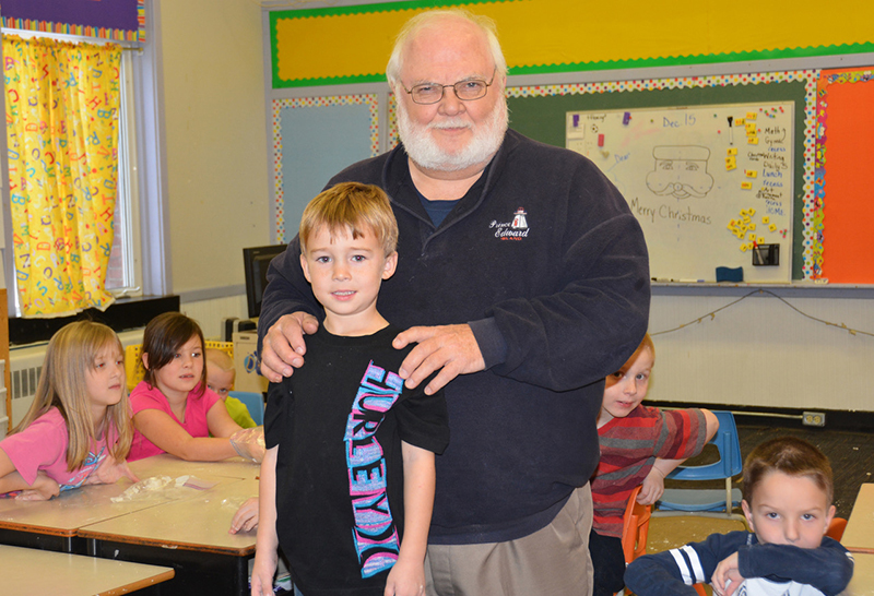 Gordon Porter and little boy smile at the camera in classroom.